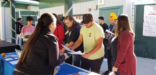 students at a vendor's table looking at informational flyers